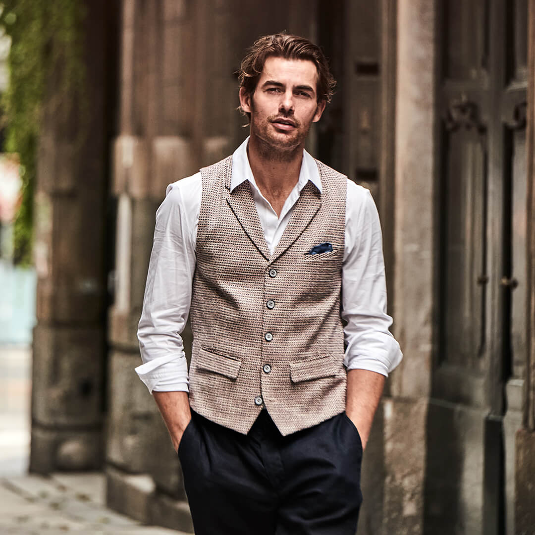 Model trägt DORNSCHILD Herrenweste mit Revers in Naturton mit fein gewebter Struktur im stilvollen Sommer-Look