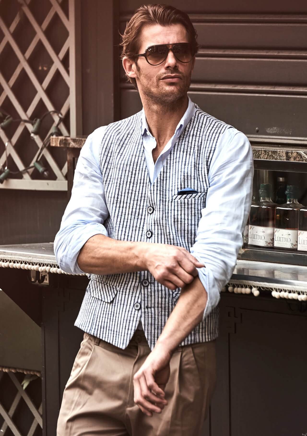 Model trägt DORNSCHILD Herrenweste in Sand mit dunkelblauem Streifenmuster im sommerlichen Styling