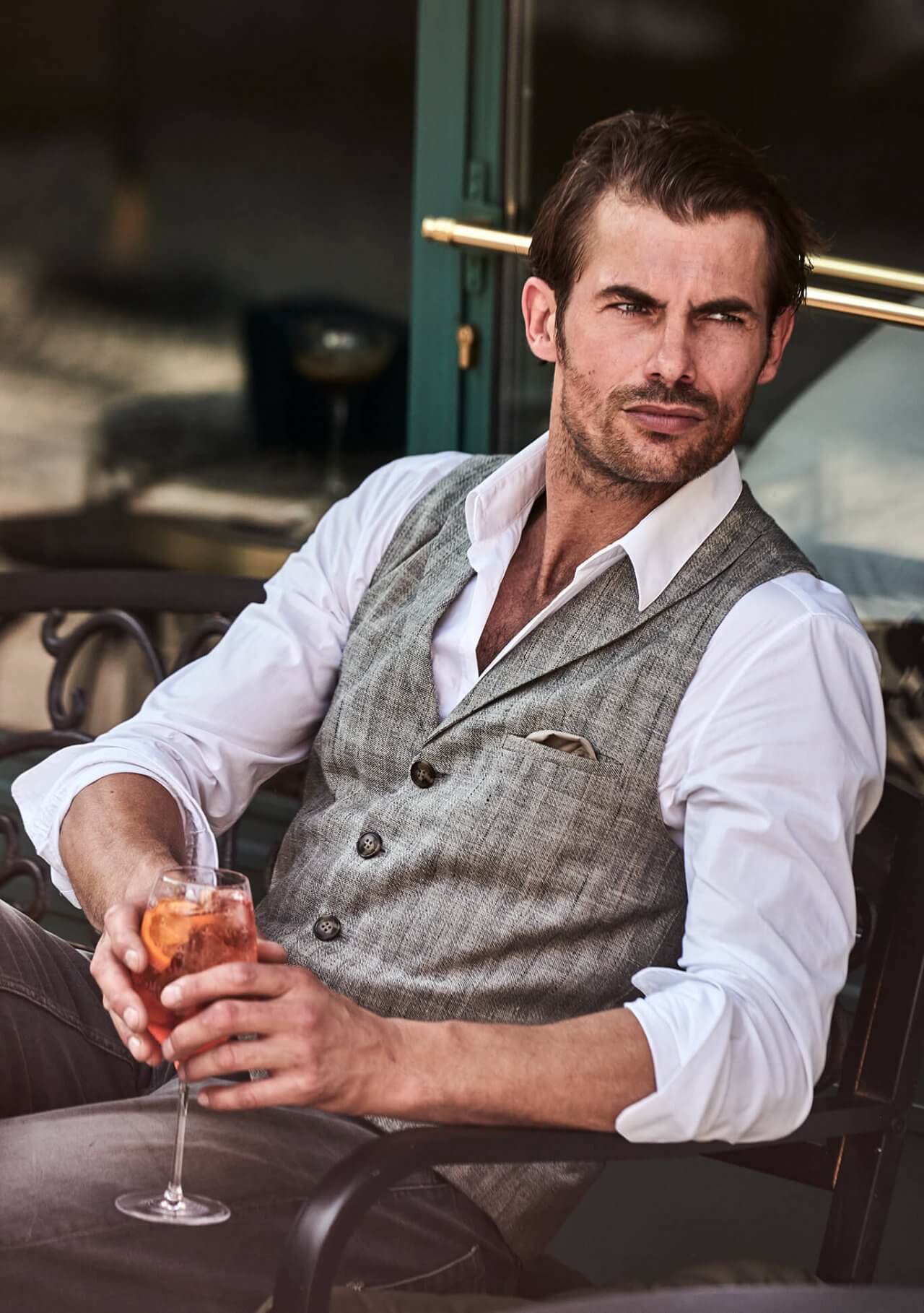 Model trägt DORNSCHILD Leinen Herrenweste mit Revers in hellem Taupe mit feinem Streifenmuster im urbanen Sommer-Look