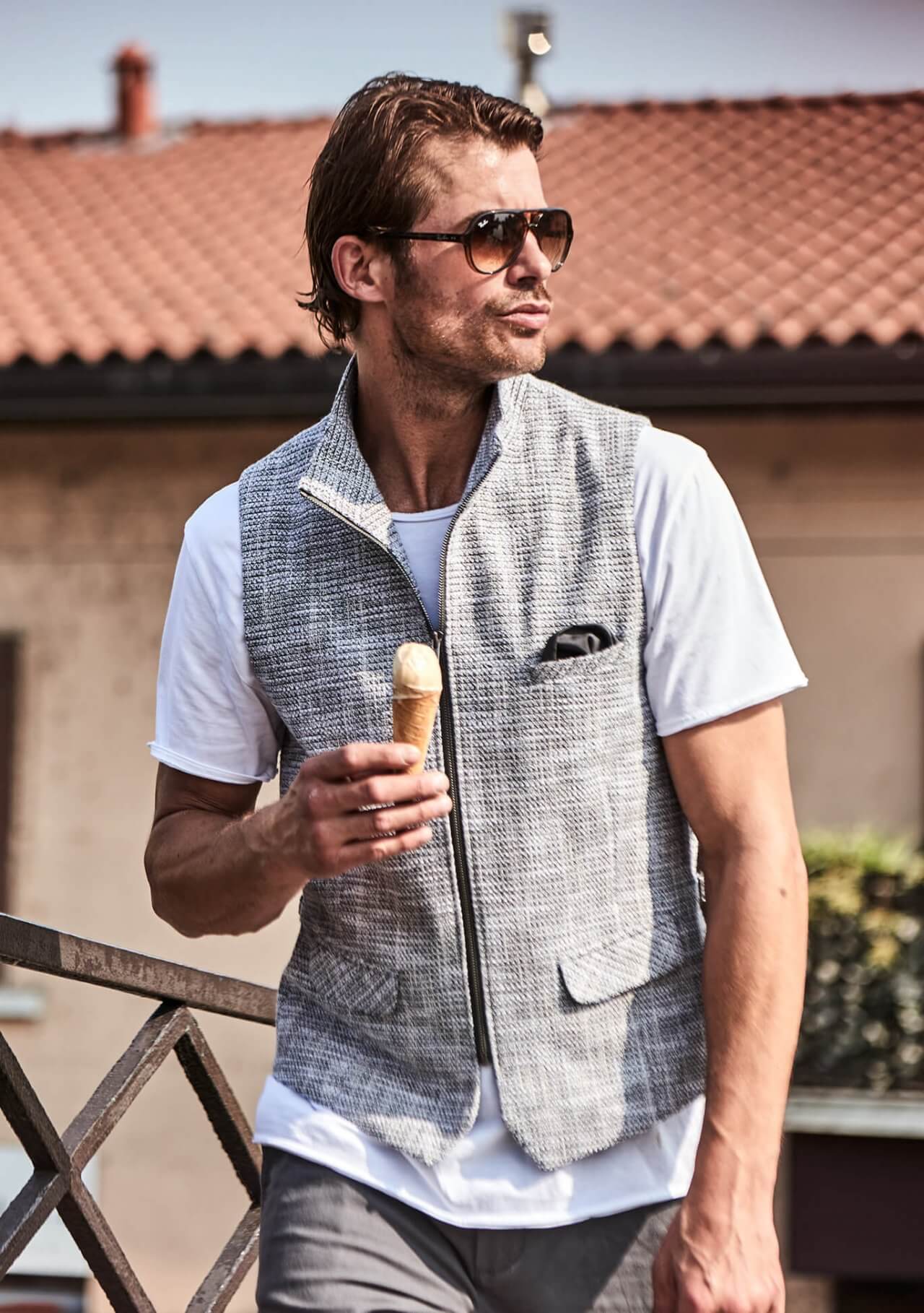 Model trägt DORNSCHILD Herrenweste mit Zipper in Grau meliert zu weißem Longsleeve und Denim im urbanen Sommer-Look