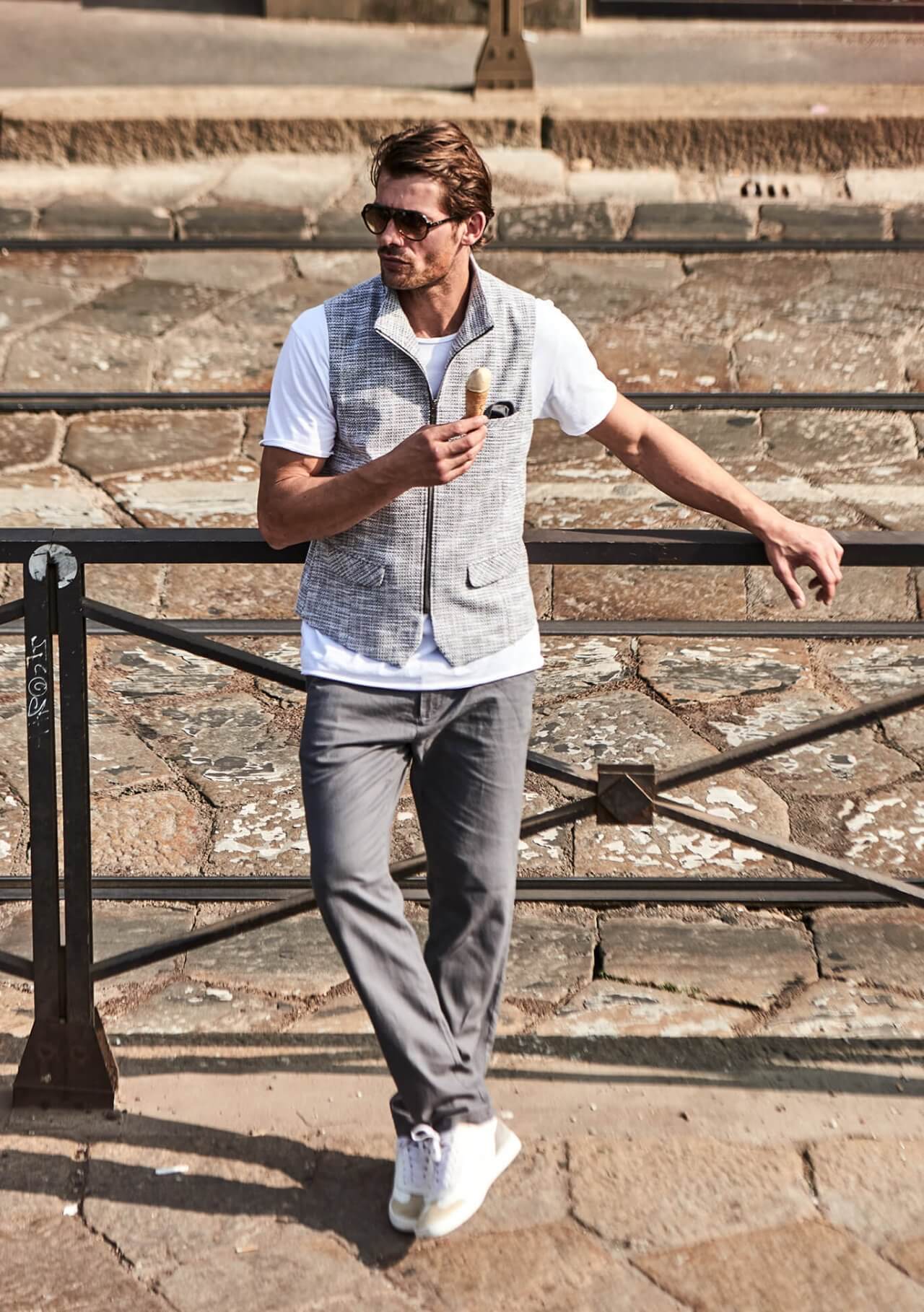 Model trägt DORNSCHILD Herrenweste mit Zipper in Grau meliert zu weißem Longsleeve und Denim im urbanen Sommer-Look