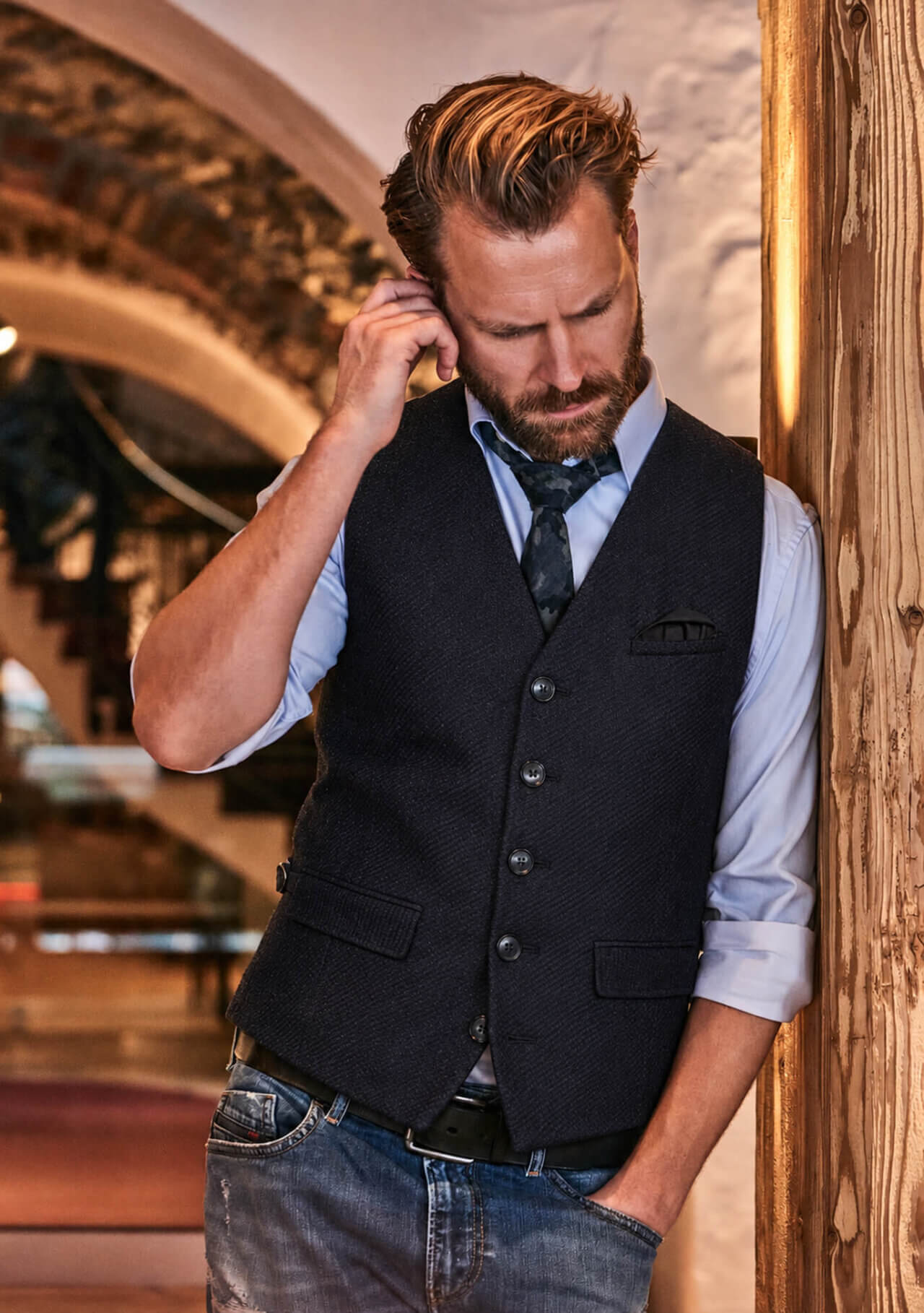 Model trägt die dunkelblaue DORNSCHILD Herrenweste HW26 W1-7 mit hellblauem Hemd, lockerer Krawatte und Jeans.