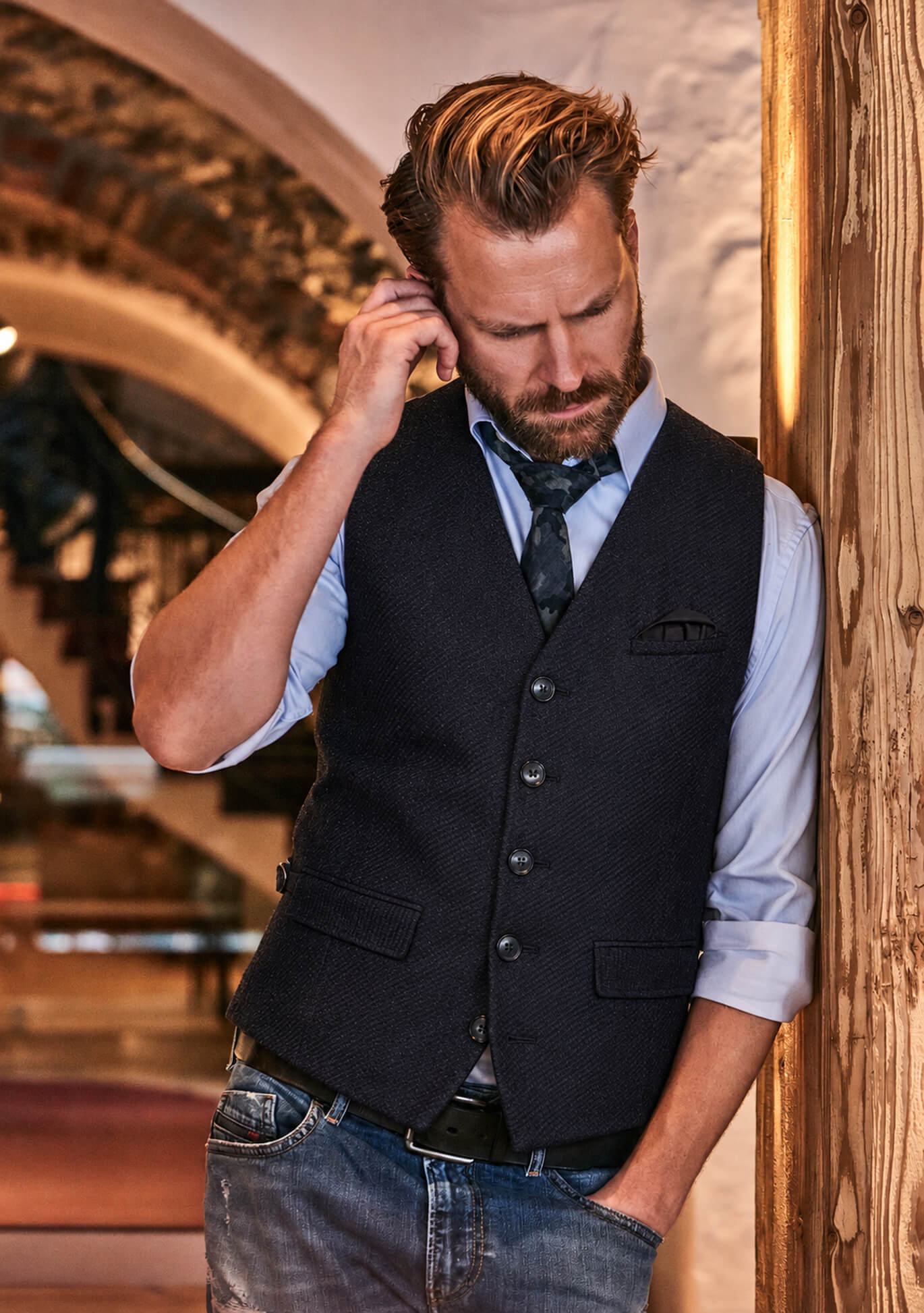 Model trägt die dunkelblaue DORNSCHILD Herrenweste HW26 W1-7 mit hellblauem Hemd, lockerer Krawatte und Jeans.
